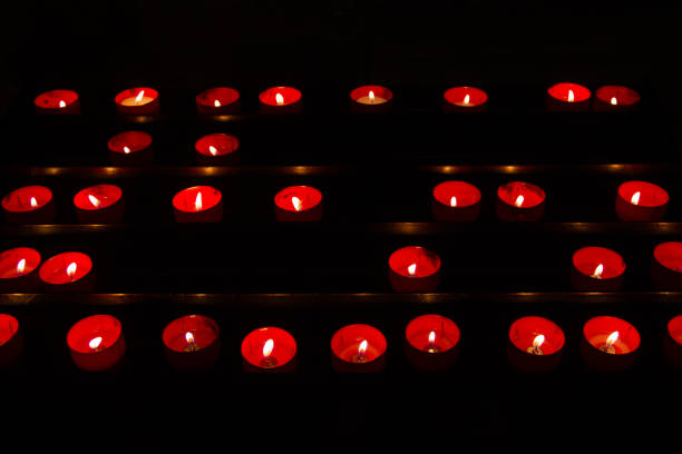 Red candle lights in the dark. Religious tradition inside church