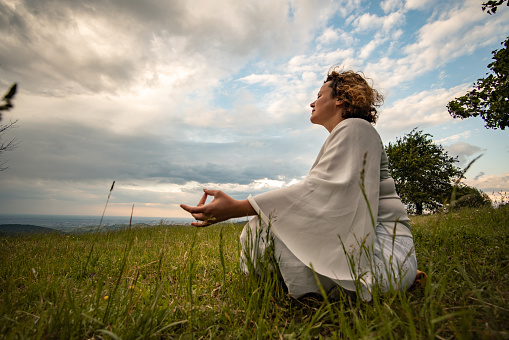 Beautiful adult woman is meditating in forest