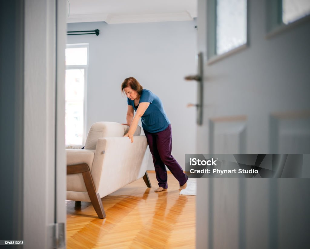 Woman suffering from dizziness with difficulty standing up while leaning on sofa Dizzy Stock Photo