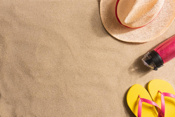 istock Summer vacation composition. Water bottle, flip flops and straw hat on sand 1248814158