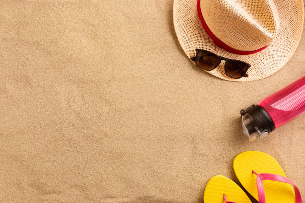 istock Summer vacation composition. Flip flops, hat and other stuff on sand background 1248815273