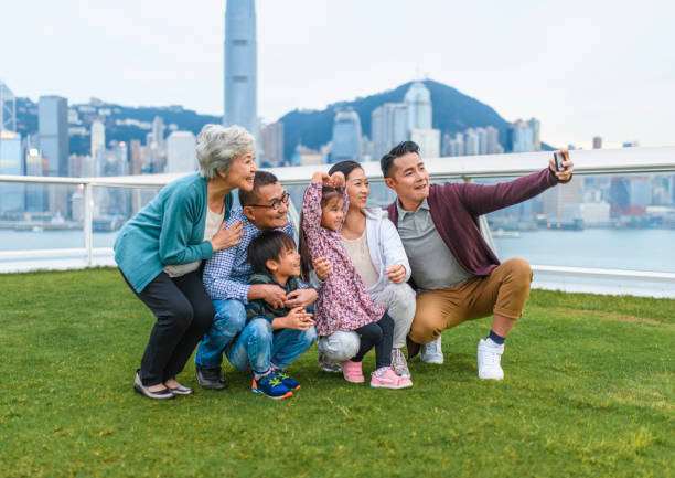 extended chinese family taking selfie at ocean terminal deck - harbour city imagens e fotografias de stock