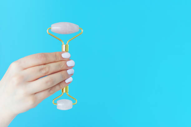 istock A woman's hand with a white manicure holds facial massage roller on a blue background 1248835649