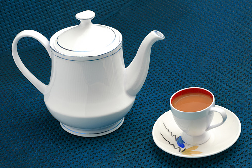 Milk tea in cup with teapot  on Blue background