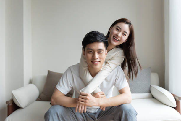 A young Asian couple taking pictures of each other on the sofa A young Asian couple taking pictures of each other on the sofa chinese couple stock pictures, royalty-free photos & images