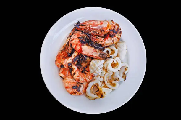 big portion of grilled sea water tiger prawn and squid served on white plated dish isolated background with clipping path