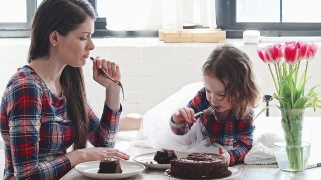 Baby girl enjoying a slice of birthday cake with her mother