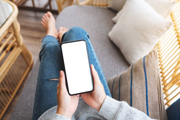 istock a woman holding mobile phone with blank desktop white screen while lying on a sofa at home 1248860340