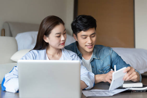 istock A young asian couple is sitting on a carpet using a computer 1248865777