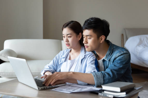 istock A young asian couple is sitting on a carpet using a computer 1248865941