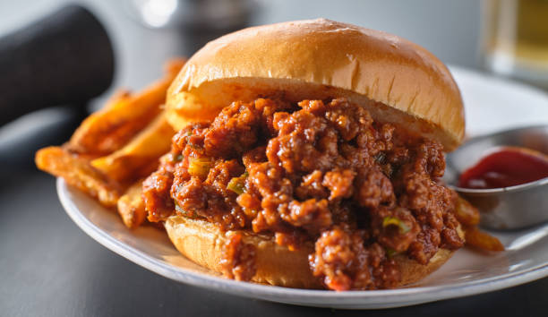 sloppy joe sandwich on plate with french fries and ketchup sloppy joe sandwich on plate with french fries and ketchup on dark table top sloppy joes stock pictures, royalty-free photos & images