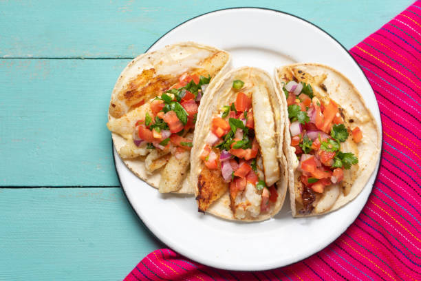 Mexican fish tacos also called Baja with fresh sauce on turquoise background