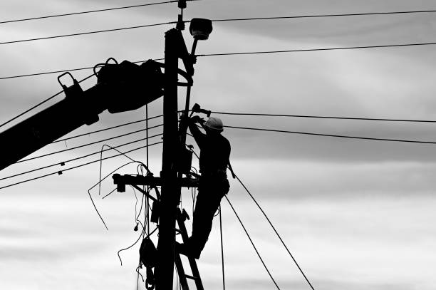 High Voltage Tower and Power Lines with Engineer Silhouette at Golden Hour