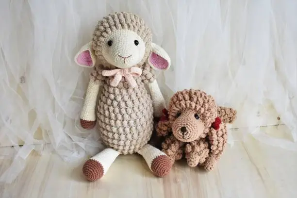 Photo of Sheep and cute poodle dog crochet, little puppy and animal toy for kids. Lamb crocheting and knitting lovely pet background with vintage theme with chiffon and wood, home decoration