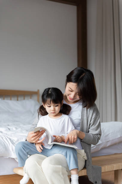 istock Young Asian mother is reading a book with her daughter 1248875556