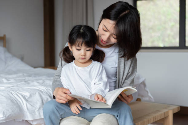 istock Young Asian mother is reading a book with her daughter 1248875604