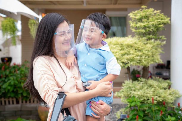 coronavirus covid-19 concept.little asian boy with mother wearing face shield mask - studen imagens e fotografias de stock