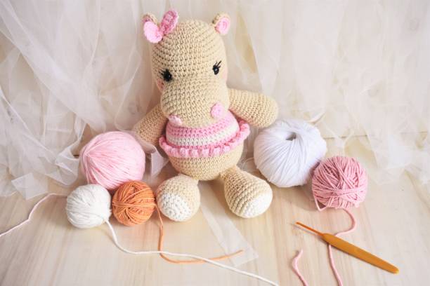 Cute hippopotamus crochet handmade toys for kids. Vintage background soft toy for children. Hippo knitting, Handmade Hippie, woolen Hippie for baby girls. Wool and crochet hook, pink pastel background. Crocheting animals for decorating on bedroom of child. Home decoration. White chiffon background and wood theme. Love animals soft good for elementary age, nursery, preschool, teens lindo hipopótamo ganchillo juguetes hechos a mano para los niños. juguete suave de fondo vintage para niños. hippo tejiendo, hippie hecho a mano, bebé hippie de lana. gancho de lana y ganchillo, fondo pastel rosa. animales de ganchillo para decorar en