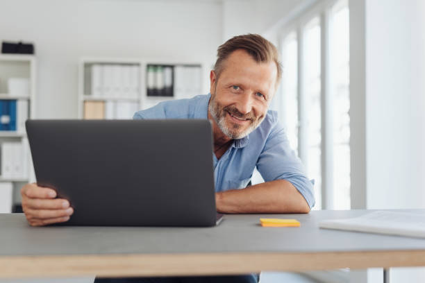 istock Smiling confident businessman seated at a desk 1248879094