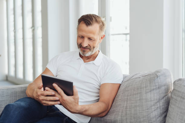 Man relaxing at home with his tablet pc stock photo