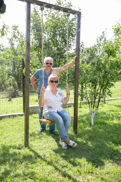 middle aged couple Senior couple on a swing. together in mature lifestyle and love concept