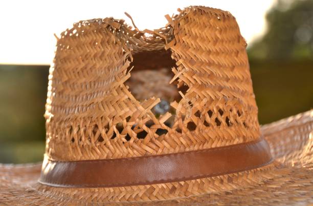 istock Old straw cowboy with a hole in it outside on a table in the sun 1248881576