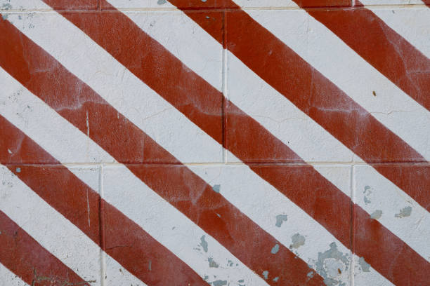 Old grungy concrete wall with peeling paint Red and white stripes