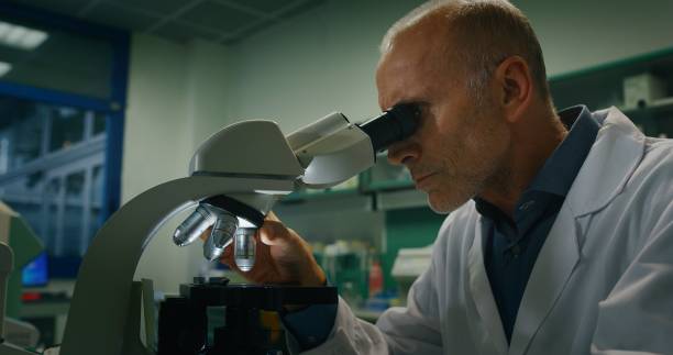istock young and charming doctor look in microscope for accomplishing some routine medical procedures in an  professionally equipped laboratory with professional development materials 1248887664