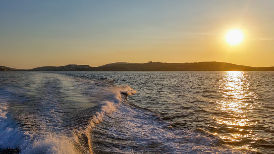 Leaving a boat wake behind while passing by the Maltese coast with a yacht.