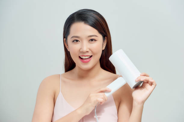 istock Smiling young woman singing while blow-dry 1248889714