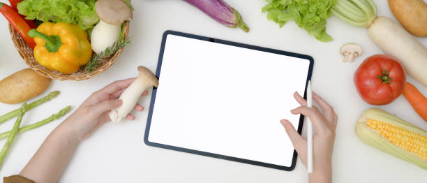 istock Young woman looking recipe on mock-up tablet while preparing ingredient for cooking with fresh vegetables 1248890919