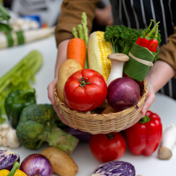 istock Hands holding basket of several fresh farm vegetables while standing at table with other fresh vegetables 1248891597