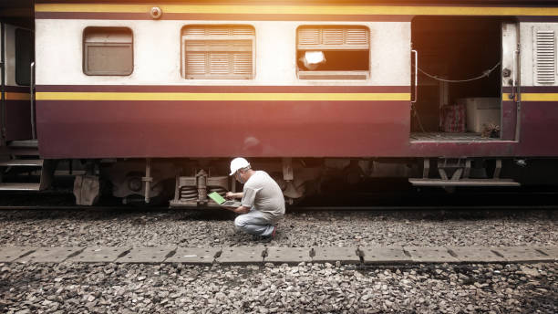 The mechanical technician is using a notebook to test the mechanics and readiness of the train while resting at the station.