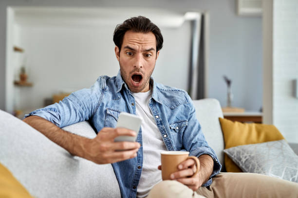 istock Young shocked man reading text message on mobile phone at home. 1248896715