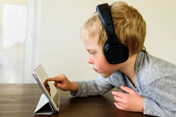 istock Little boy learning at home. Watching webinar on mobile tablet 1248899157