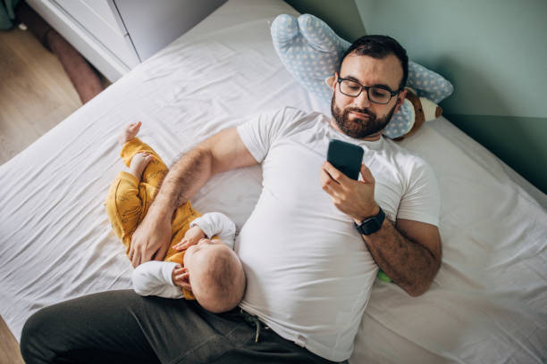 istock Father lying with baby son on bed and using smart phone 1248900296