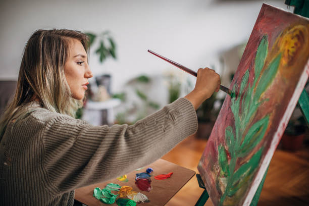 istock Creative woman painting on a canvas in her home studio 1248910425
