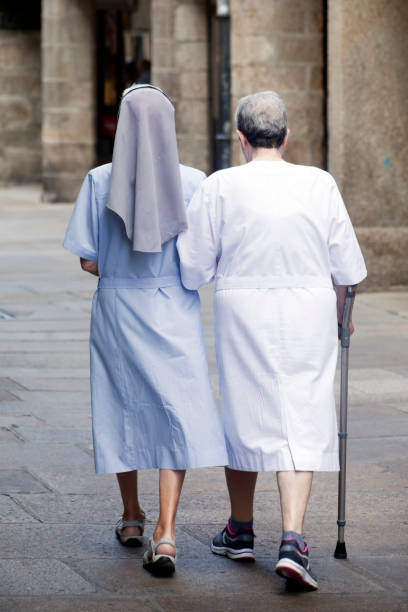 вид сзади монахини и старшей женщины, идущей по улице. - garment fragility women skirt стоковые фото и изображения