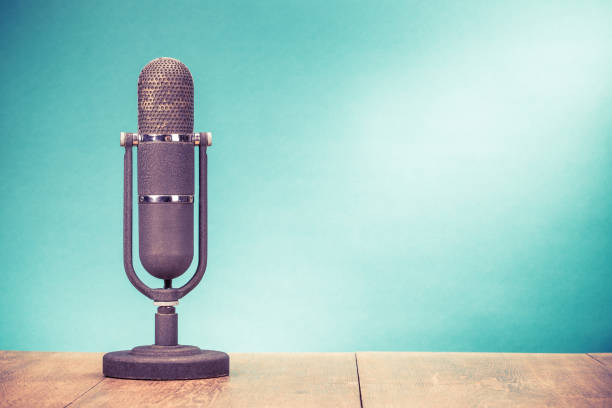 istock Retro studio microphone from 50s on table front gradient aquamarine wall background. Vintage old style filtered photo 1248913911