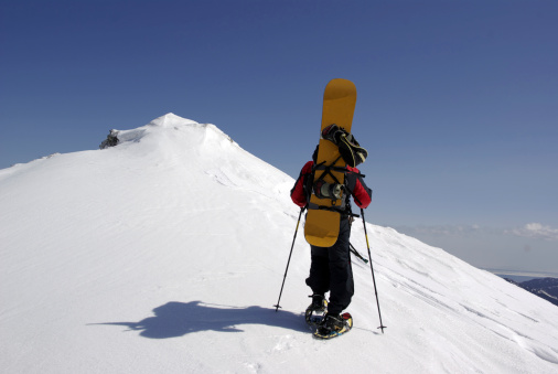 Snowboarder ascend on mountain peak