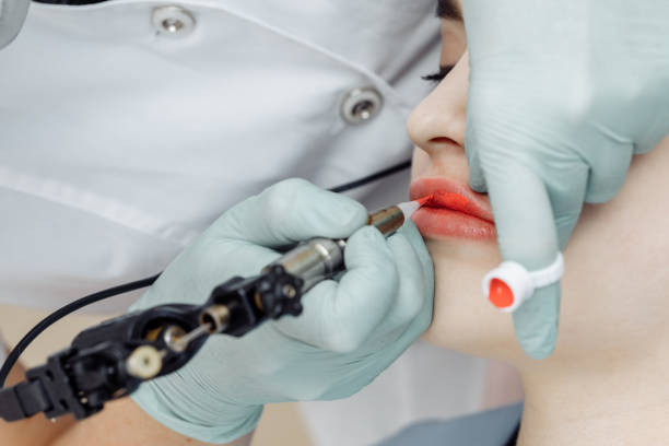 istock Woman having permanent makeup on lips in beauty salon 1248930947