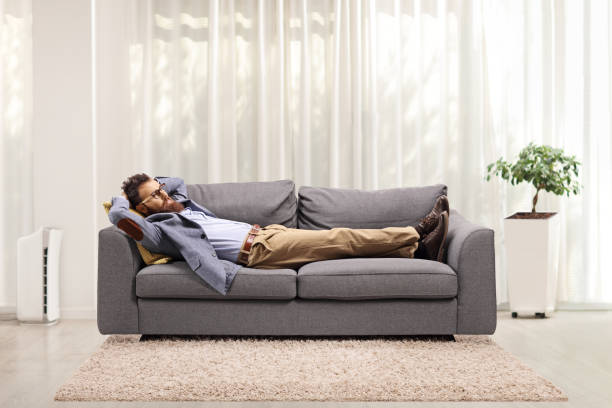 istock Bearded man lying on a gray sofa in a living room 1248930991