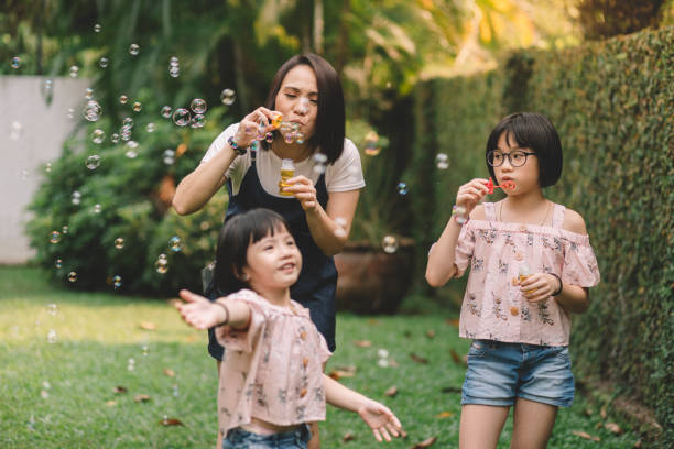 家の裏庭で泡を吹くアジアの中国人の母と娘 - bubble wand child blowing asian ethnicity ストックフォトと画像