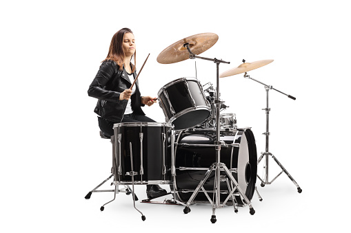 Young female musician playing a drum kit isolated on white background