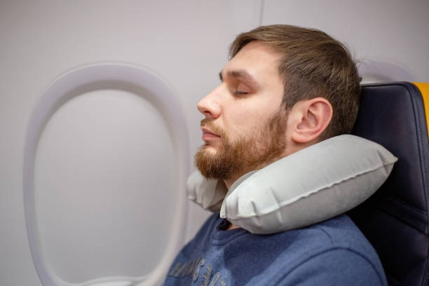 若い魅力的なヨーロッパ人男性は、飛行機の中でインフレータブルネック枕を使用して休んで、ひげを眠って30年。快適さ、飛行機の中のストレス、輸送、旅行。ストック写真。 - armchair comfortable relaxation headphones ストックフォトと画像
