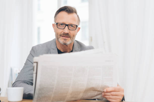 istock Mature man wearing glasses reading newspaper 1248946190