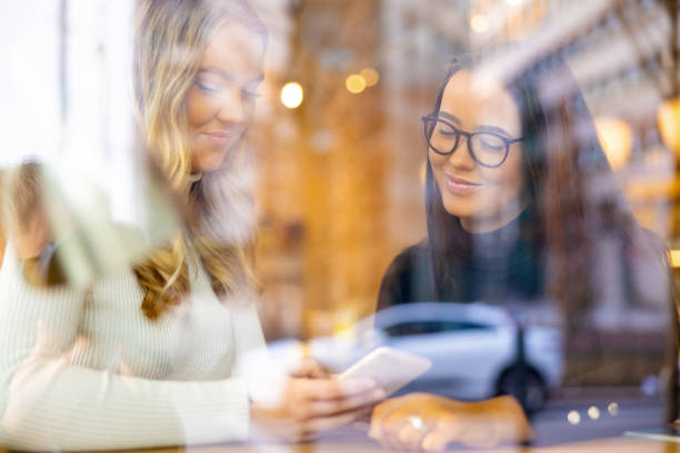 istock Two Smiling Friends Looking At Smartphone In Cafe 1248946207