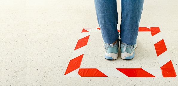 Red striped line sign for keeping social distance. Woman standing behind a warning line during covid 19 coronavirus quarantine. Safe shopping, Social distancing concept. Web banner with copy space.