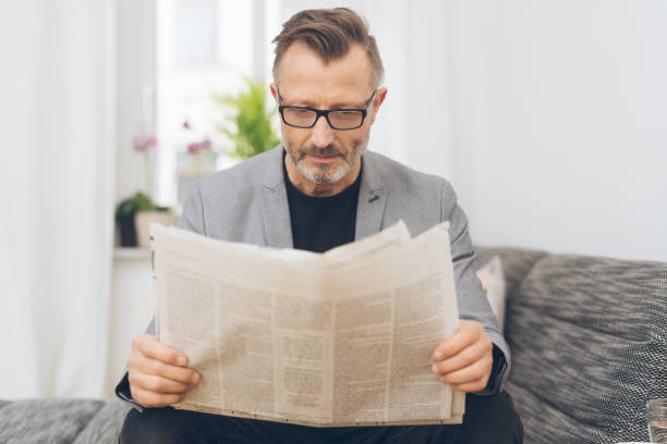 istock Middle-aged man sitting reading the newspaper 1248947260