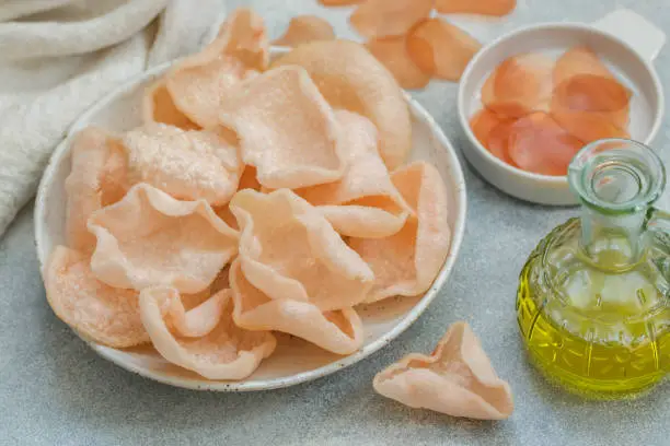 Photo of Delicious crispy chips made of starch, flour and shrimp. Bowl of Krupuk (prawn crackers). Traditional Asian snack. A dish of Indonesian, Malaysian, Chinese, Korean, Japanese cuisine. Selective focus